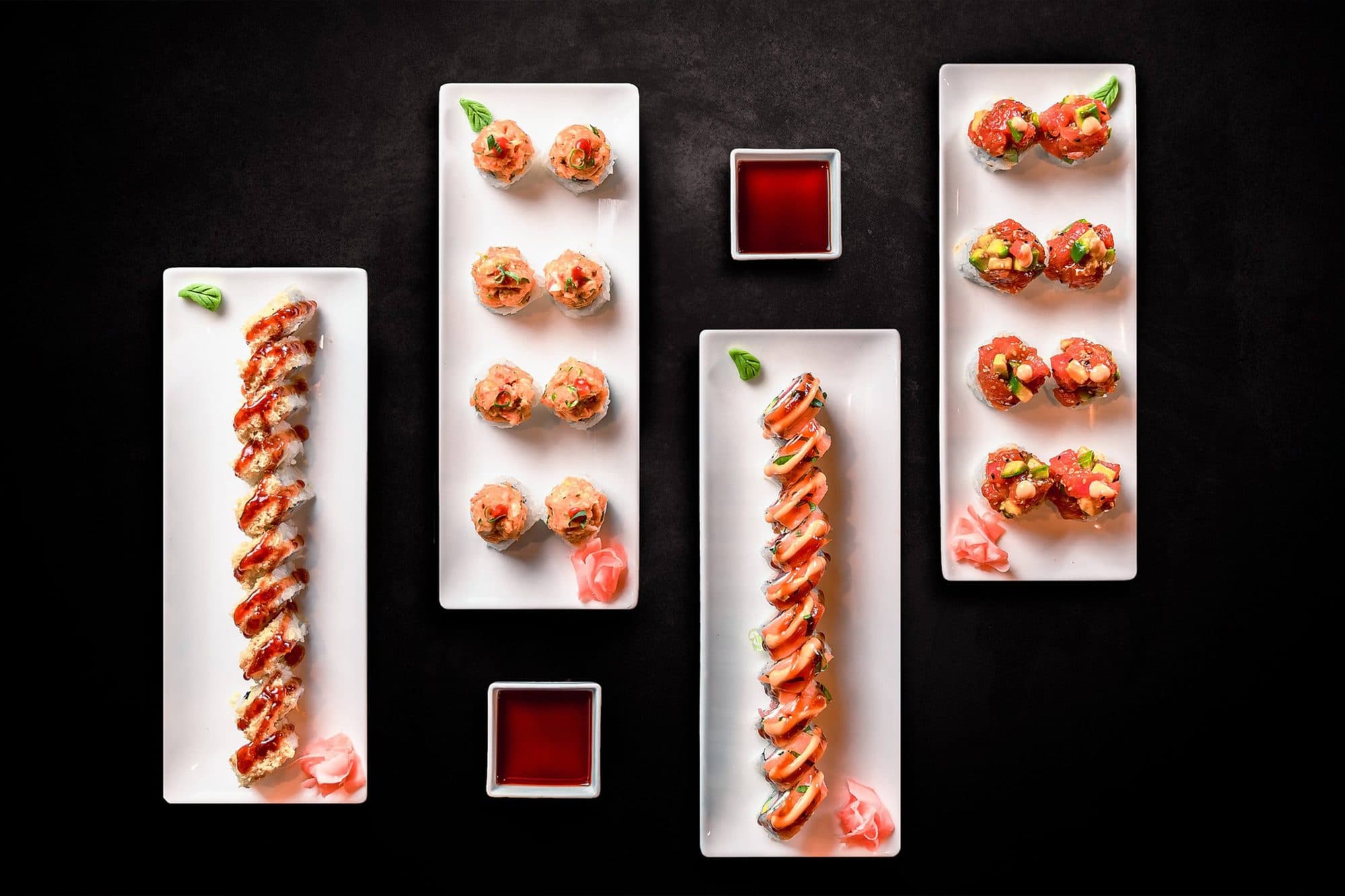 Sushi-Rollen auf weißen Platten mit Sojasauce